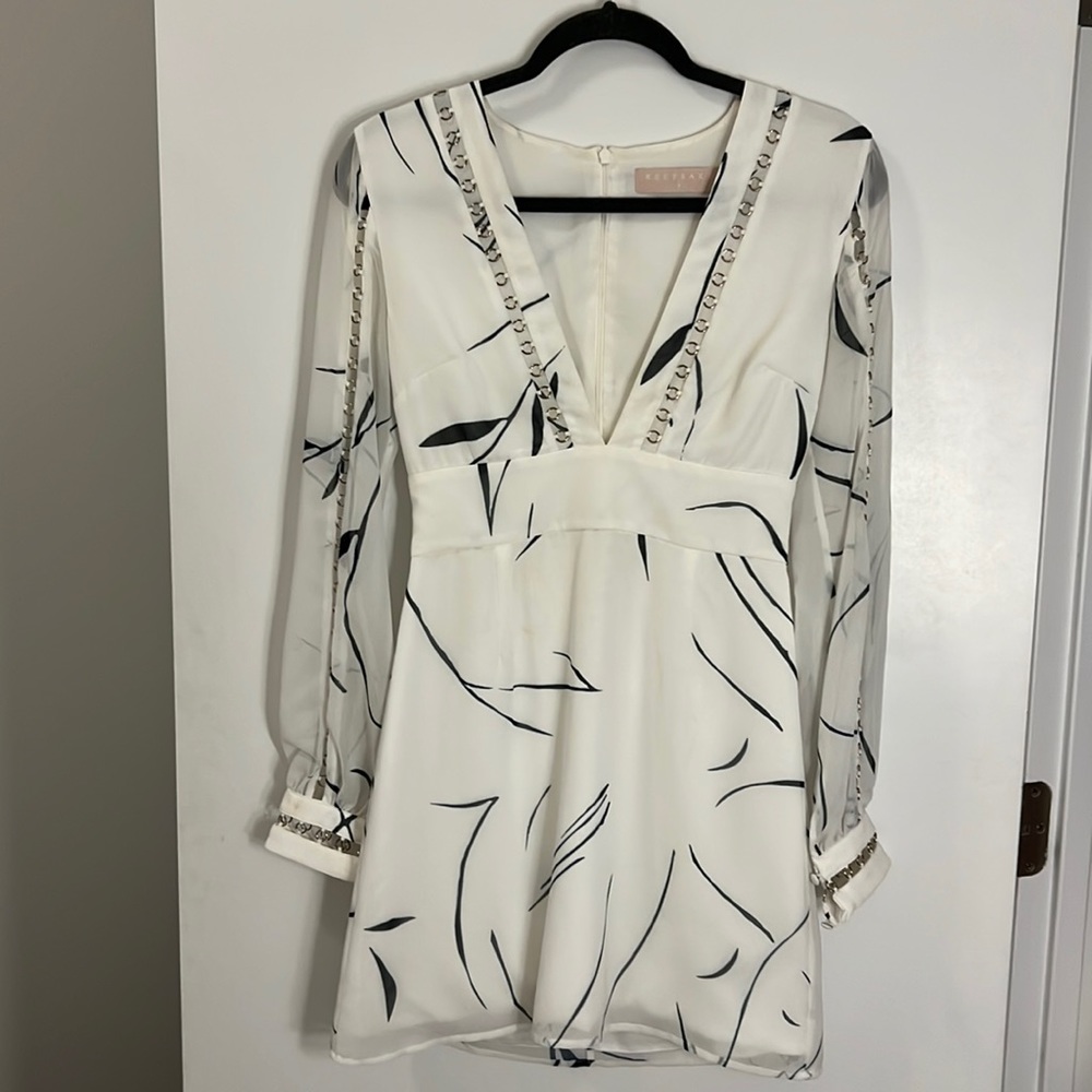 White mini dress with blue design. Sheer sleeves with cut out detailing.